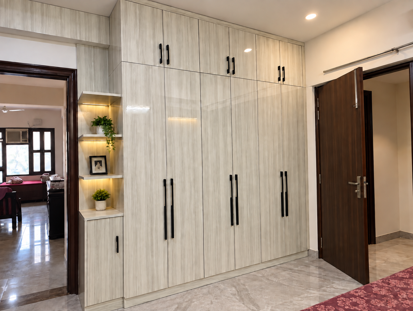 Floor-to-ceiling wood-finish wardrobe with black handles in a Gurugram bedroom